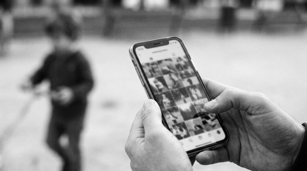 Móvil con fotos y un niño al fondo: publicar imágenes de menores en redes