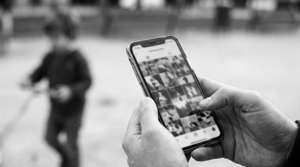 Móvil con fotos y un niño al fondo: publicar imágenes de menores en redes